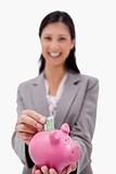 Money being put into piggy bank by smiling businesswoman