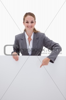Smiling bank employee pointing down at blank sign