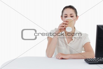 Businesswoman drinking a takeaway tea while using a computer