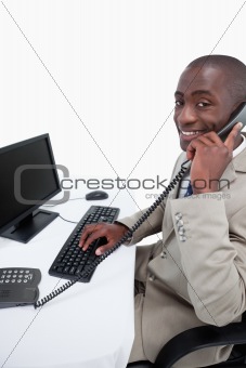 Side view of a male secretary answering the phone while using a monitor