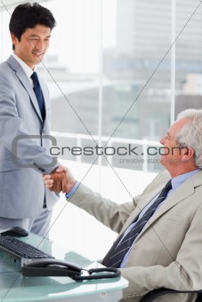 Portrait of a smiling employee shaking the hand of his manager