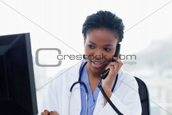 Female doctor on the phone while using a computer