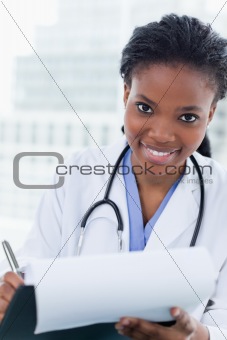 Portrait of a smiling female doctor signing a document