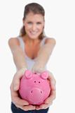 Portrait of a beautiful woman showing a piggy bank