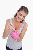 Portrait of a woman putting a note in a piggy bank