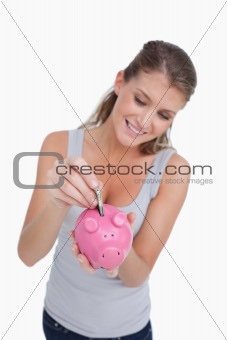 Portrait of a woman putting a note in a piggy bank
