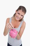 Portrait of a smiling woman putting a note in a piggy bank