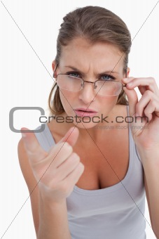 Portrait of a serious woman with glasses pointing at the viewer