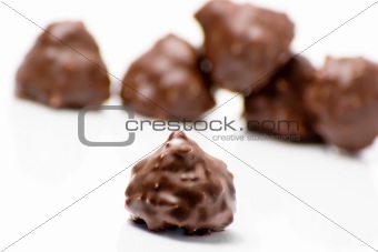 Delicious chocolates and nuts on white background
