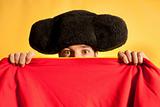 Bullfighter afraid with big montera hidden behind cape humor spanish colors 