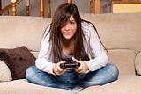 Young female playing video-games concentrating on sofa at home