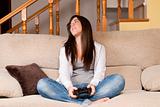 Young female lose playing video-games concentrating on sofa at home