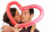 Young couple kissing through balloon heart surprise isolated