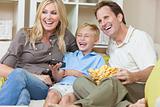 Happy Family Sitting on Sofa Laughing Watching Television