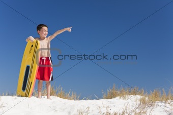 Young Boy Child on A Beach with Surfboard Pointing