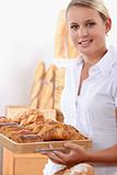 Young female baker with croissants and pain au chocolats
