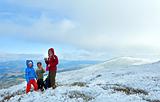 Family on autumn  mountain plateau with first winter snow