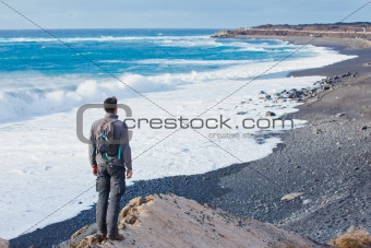 Young man hiking and looking up to the sea