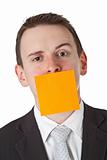 Businessman with a blank  adhesive note over his mouth