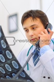 Medical doctor holding patients tomography and speaking phone