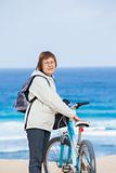 A nice senior lady riding a bike on the beach.