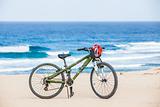 Bicycle with helmet, stand on the beach.