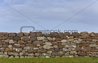 stone wall in evening light with grass and sky