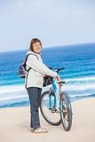 A nice senior lady riding a bike on the beach.