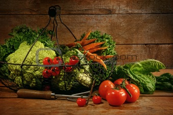 Freshly picked vegetables in basket in wooden table