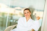 Portrait of smiling woman in bathrobe sitting on terrace