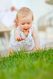 Happy baby trying to touch grass
