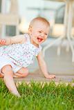 Smiling baby touching grass with leg