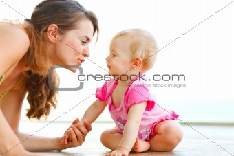 Young mother playing with baby on floor