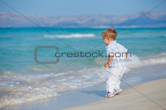 Young cute boy playing happily at pretty beach