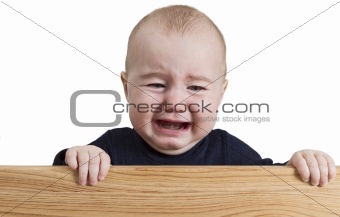 crying young child holding wooden board