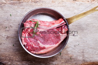raw t bone steak in a copper pan 