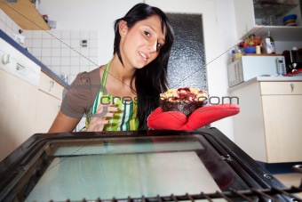 woman fetching a cake from an oven 