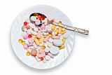 Lot of colored pills on plate and spoon