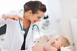 Pediatric doctor playing with baby on survey