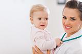 Portrait of pediatrician doctor with distrustful baby