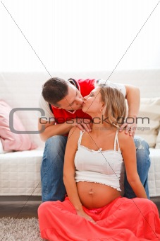 Portrait of pregnant woman with husband kissing