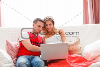 Happy young woman with husband working on laptop