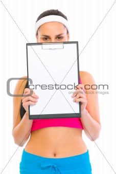 Fitness girl hiding behind blank clipboard