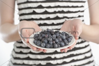 Young woman holding a plate with blueberries