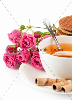 tea in cup with biscuits and bouquet roses