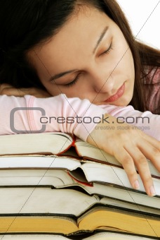 Tired girl sleeping on books stack