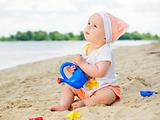 baby girl playing on the beach with sand.