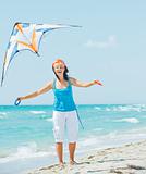Woman on beach playing with a colorful kite