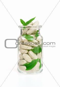Herbal supplement pills and fresh leaves  in glass - alternative medicine concept