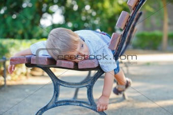 Cute little boy relaxing on bench in a city